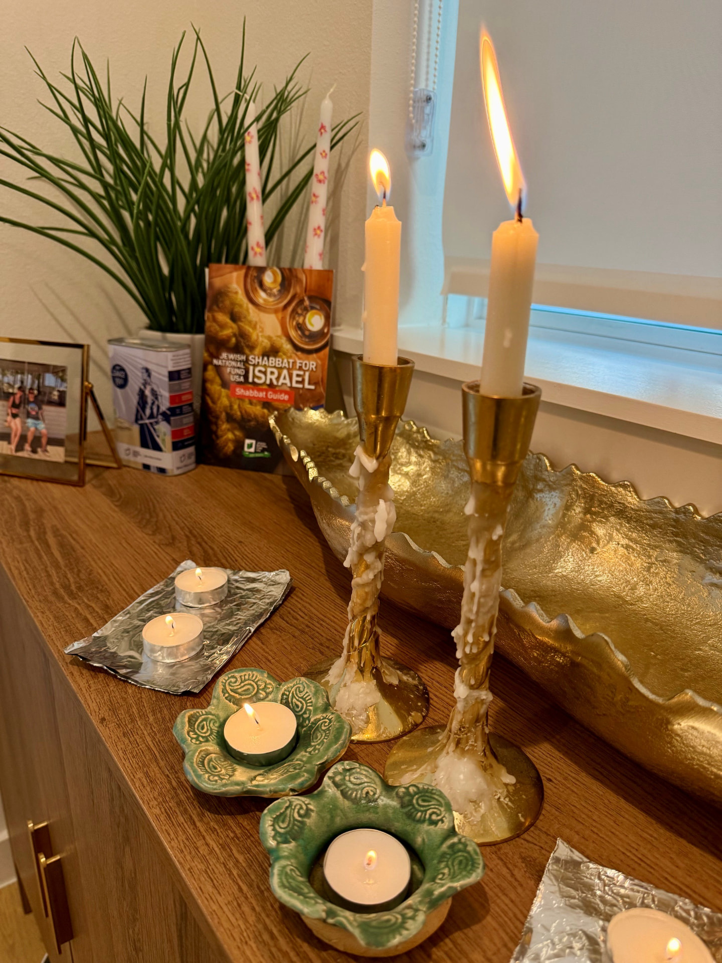 Two lit Shabbat candles beside a braided challah on a navy tablecloth